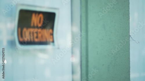 Defocused close up of No Loitering sign in store window
