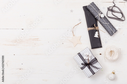 Top view on nice Christmas gifts packed in black and striped paper and decorated with stars on wooden background. Presents and decor elements. Holidays and winter concept.