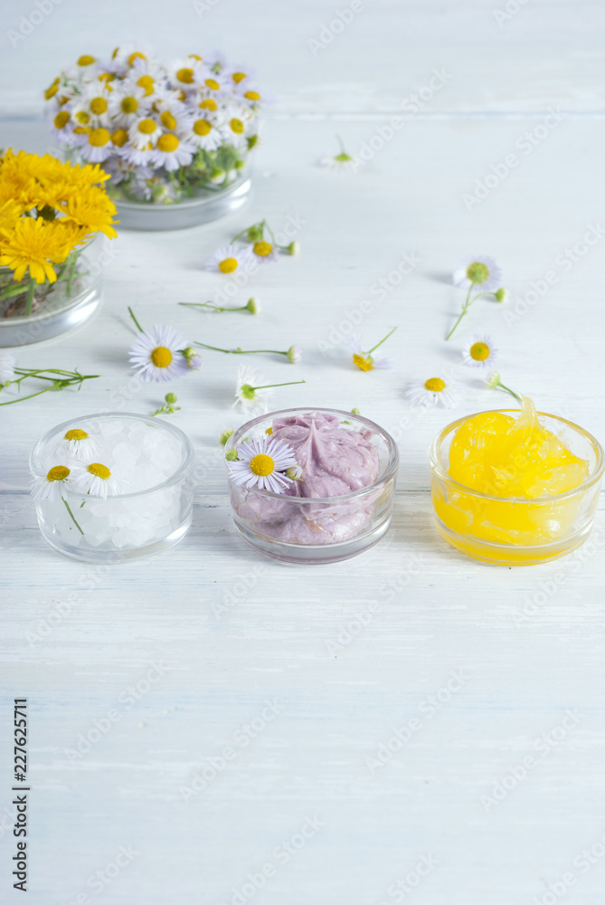 cosmetic product samples with herbal flowers on white wooden table cosmetic product samples with herbal flowers on white wooden table