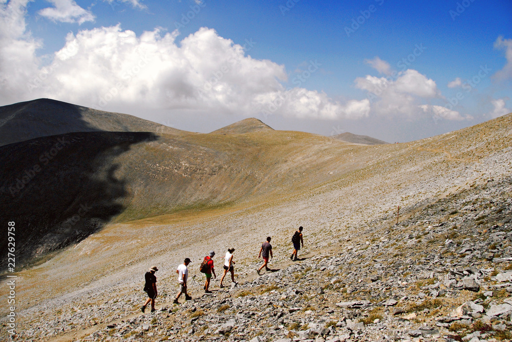 Mountain trekkers on Mount Olympus in central Greece, through the stone path, towards the Skolio summit (2.912 m.), on the way of the E4 European long distance path.