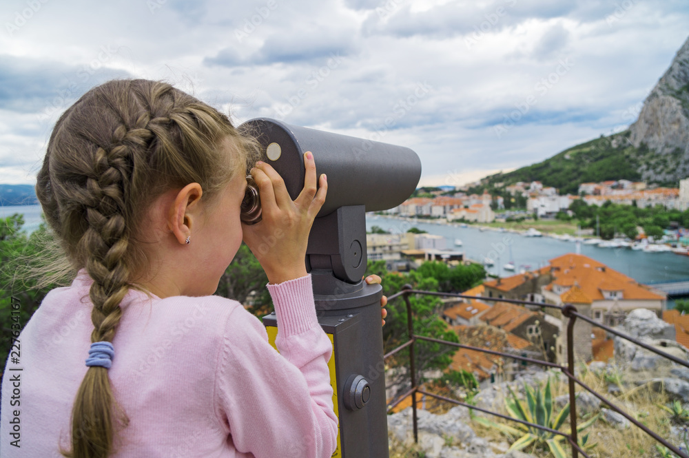 Little girl using coin operated panoramic telescope.