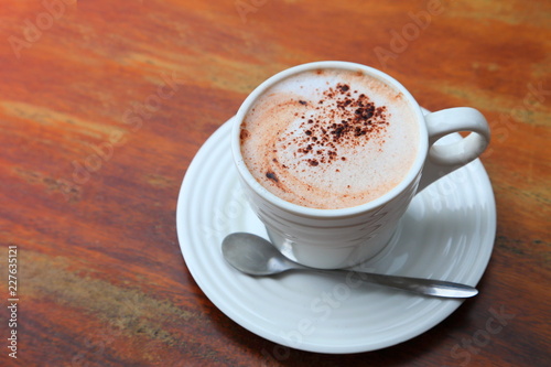 A cup of hot chocolate with cocoa powder served on wooden table