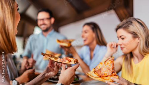 Close-up image of friends eating pizza.