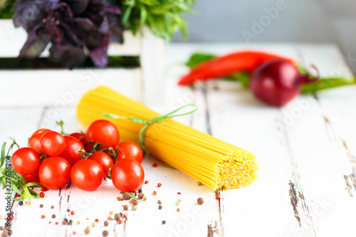 Cherry, tarragon, spaghetti, chili pepper, basil, spices Ingredients for cooking pasta. Food background
