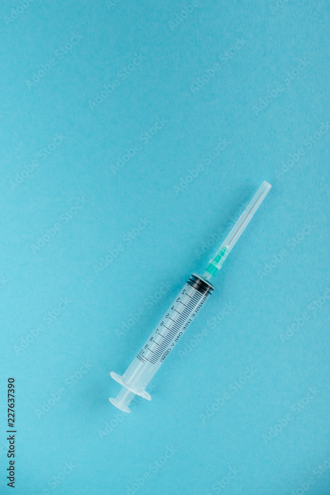 Transparent syringe with a needle, on a background. No liquid in the syringe. Single use only