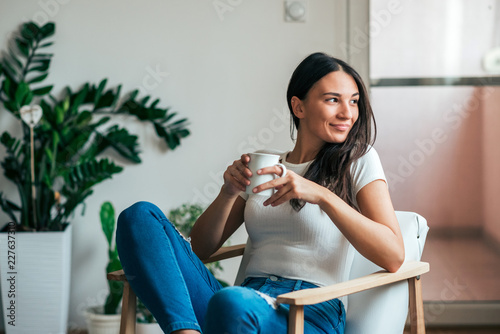 Canvas-taulu Beautiful young woman drinking tea at home. Looking away.
