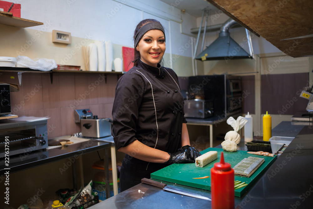 Obraz premium woman chef prepares sushi on restaurant kitchen