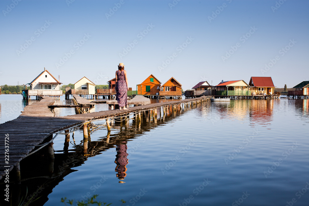 woman walking on the planks at floating village on lake Bokod, Hungary woman walking on the planks at floating village on lake Bokod, Hungary