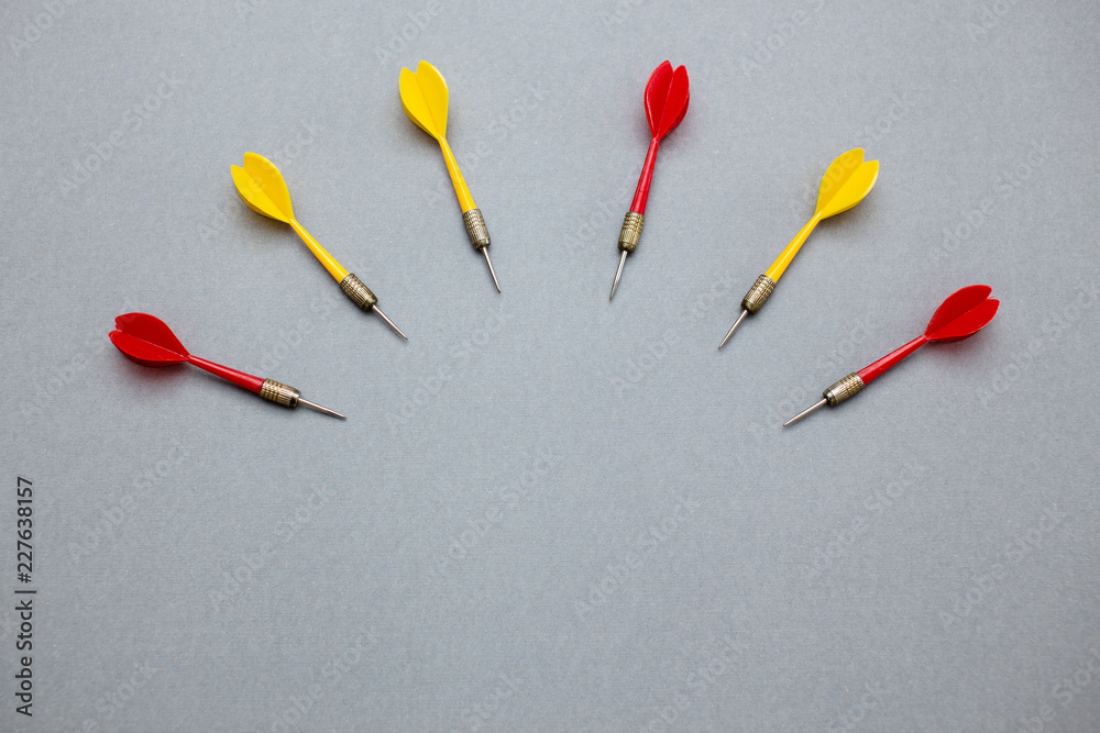 darts red and yellow on gray paper background darts red and yellow on gray paper background