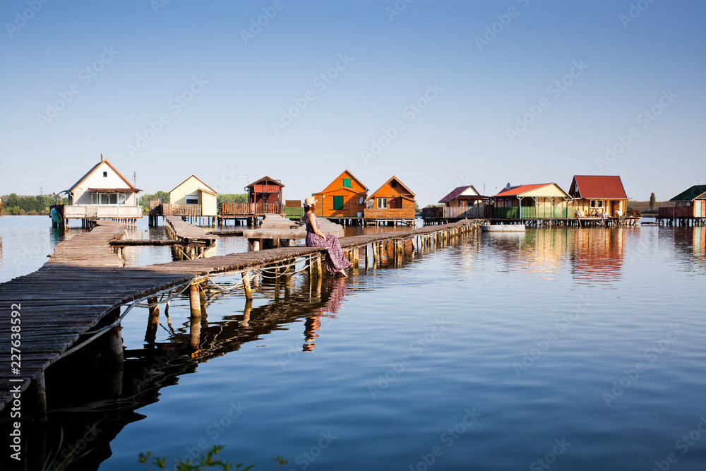 woman walking on the planks at floating village on lake Bokod, Hungary woman walking on the planks at floating village on lake Bokod, Hungary