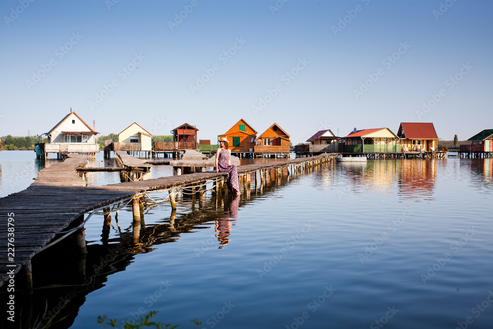 Fototapeta premium woman walking on the planks at floating village on lake Bokod, Hungary