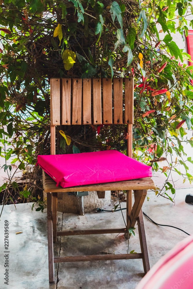 Naklejka premium Wooden chair with crooked pink pillow