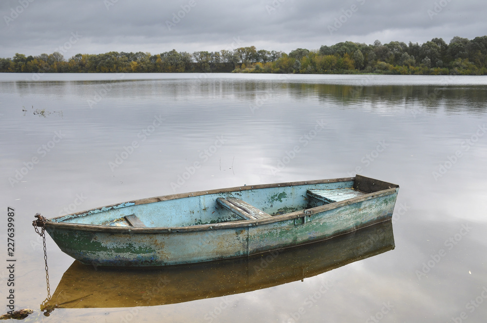 Old boat on water tied to shore 