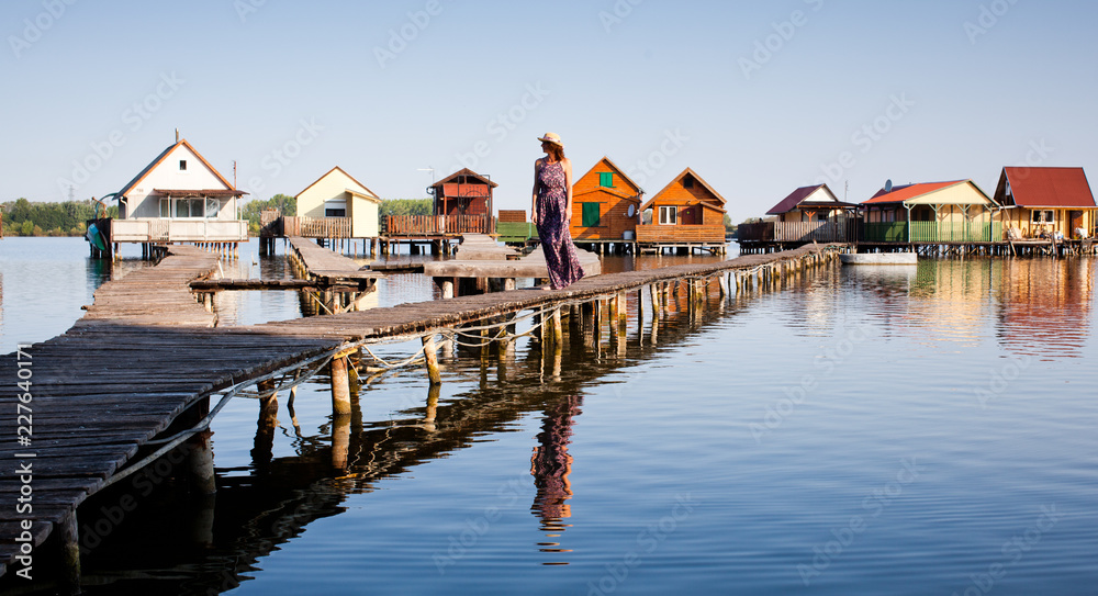 Fototapeta premium woman walking on the planks at floating village on lake Bokod, Hungary