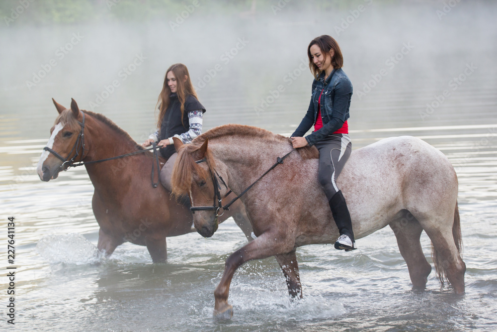 Two young women on horses stay in the lake Two young women on horses stay in the lake