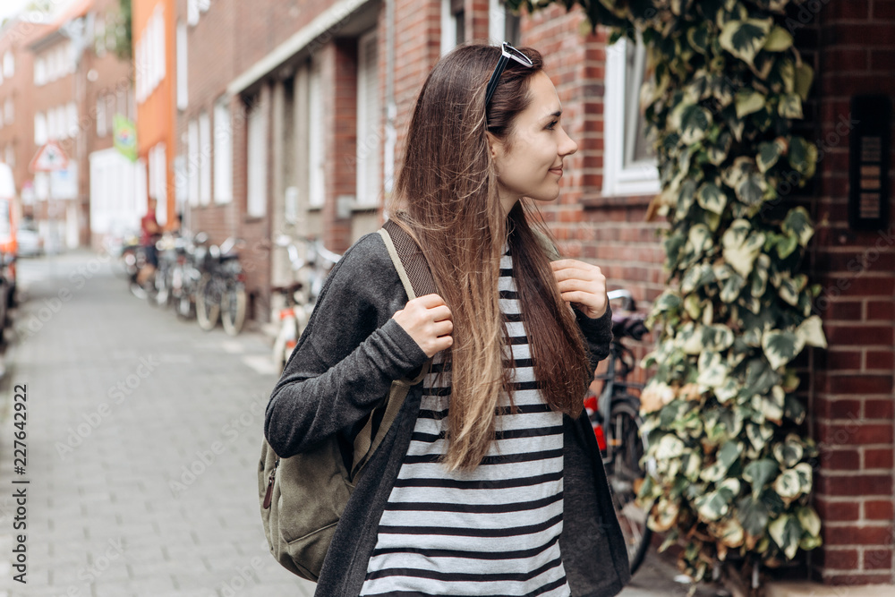 Tourist with a backpack is looking for booked online accommodation in an unfamiliar city. Or a student girl with a backpack is walking through the city. Tourist with a backpack is looking for booked online accommodation in an unfamiliar city. Or a student girl with a backpack is walking through the city.