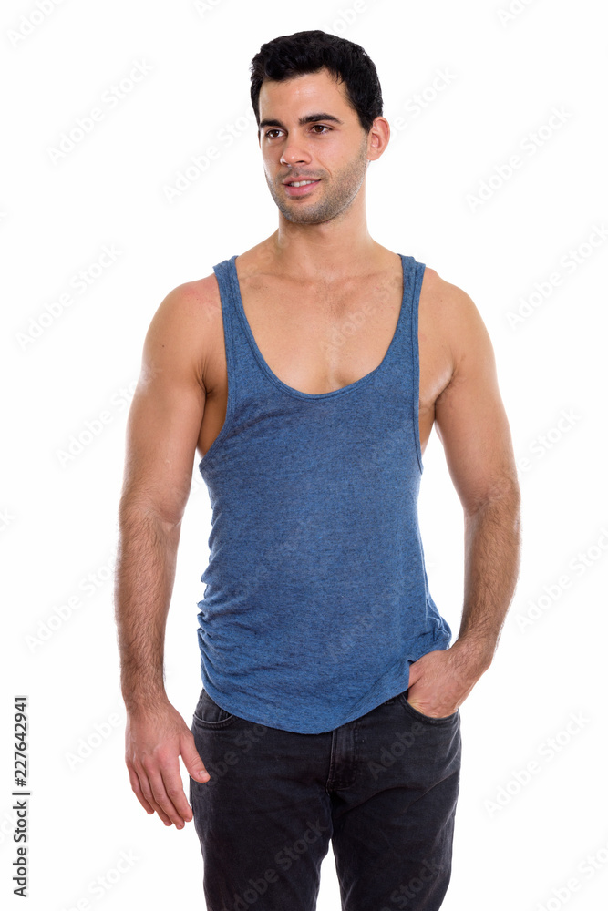 Studio shot of young happy handsome Hispanic man smiling while t