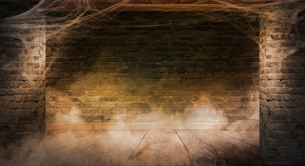 The background of the old brick wall, cracks in the wall, cobweb, neon light. Old basement room with cobwebs, smoke, smog. Dark gloomy background for the holiday of Halloween.