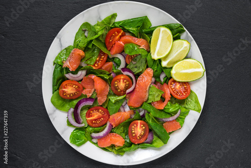 Salmon salad with spinach, cherry tomatoes, red onion, lemon and basil. healthy food concept
