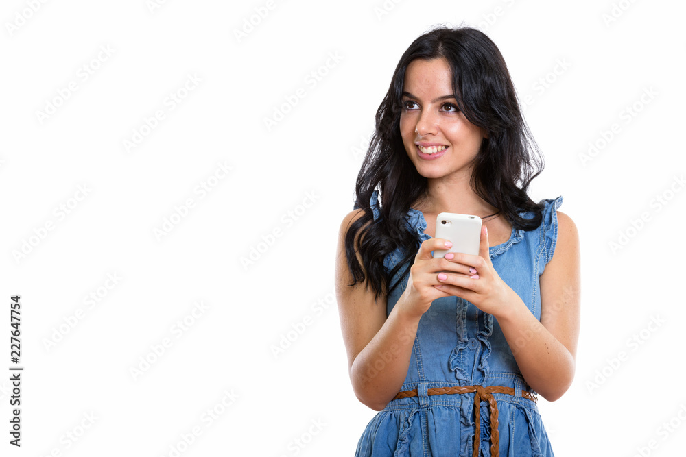 Thoughtful young happy Spanish woman smiling while holding mobil Thoughtful young happy Spanish woman smiling while holding mobil