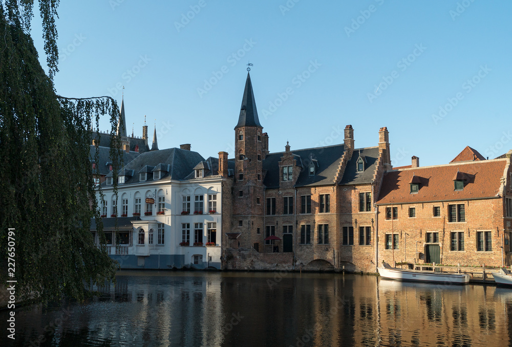 Old Bruges buildings reflecting in water canal in historical centre of Brugge