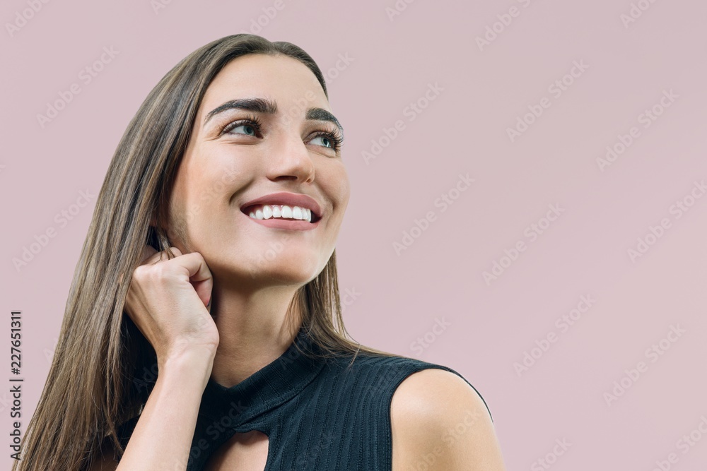 Closeup portrait of young smiling woman, caucasian female's face on beige pink pastel background Closeup portrait of young smiling woman, caucasian female's face on beige pink pastel background