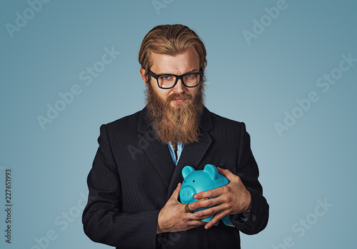 Young greedy stingy business man holding piggy bank photo