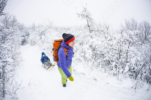 A woman is carrying a child on a sled.