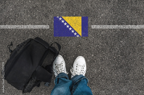 Valokuva man with a shoes and backpack is standing on asphalt next to Bosnia and Herzego