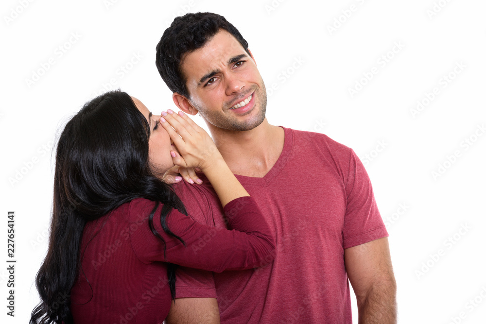Studio shot of young happy couple smiling with woman whispering Studio shot of young happy couple smiling with woman whispering