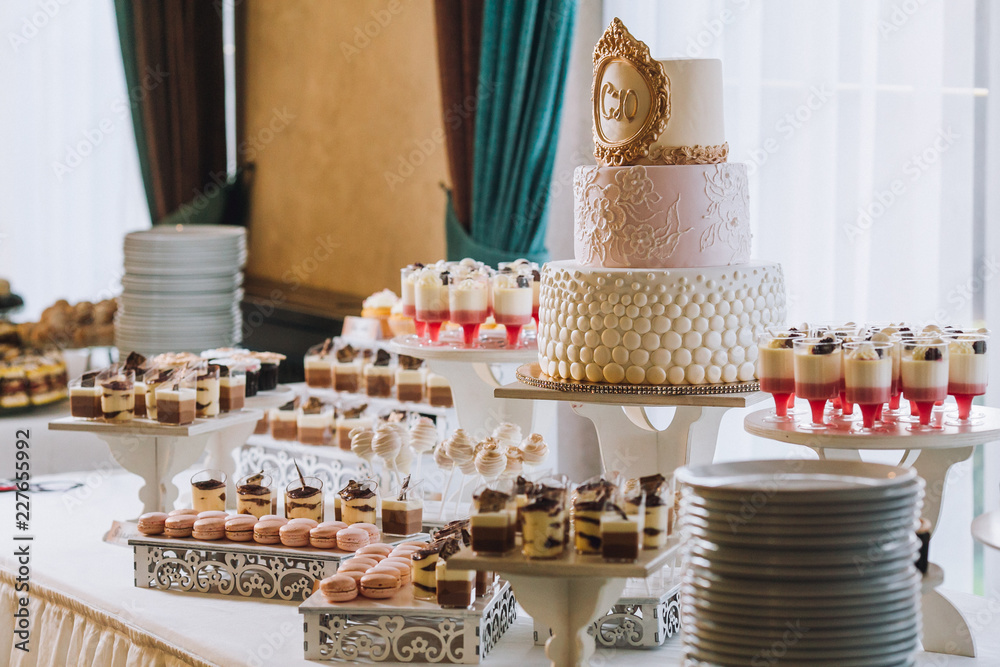 Candy bar with a lot of cookies and fruits during the wedding. chocolate fountain and wedding cake. Coktails and drink at the table