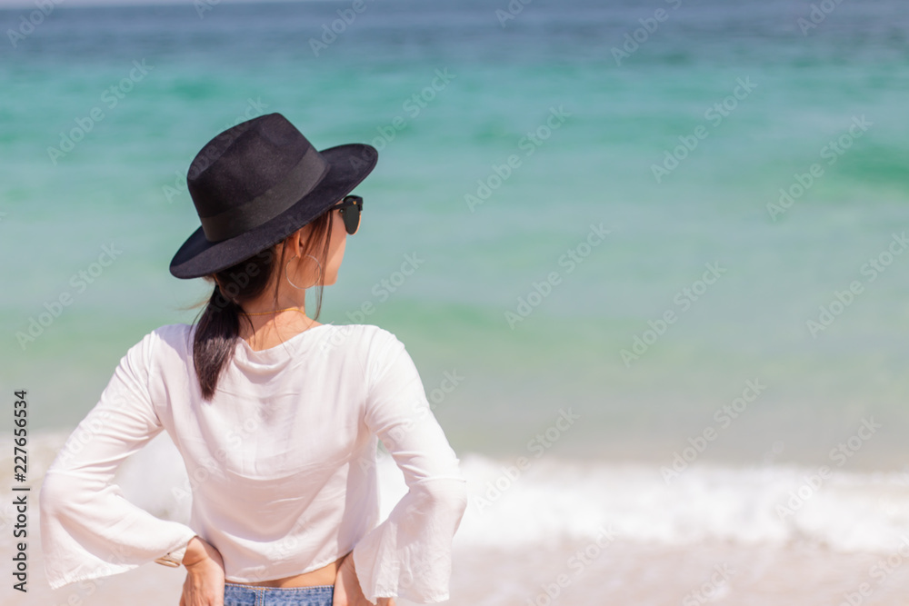 Beautiful women in white and wearing sunglasses are watching the sea in summer.
