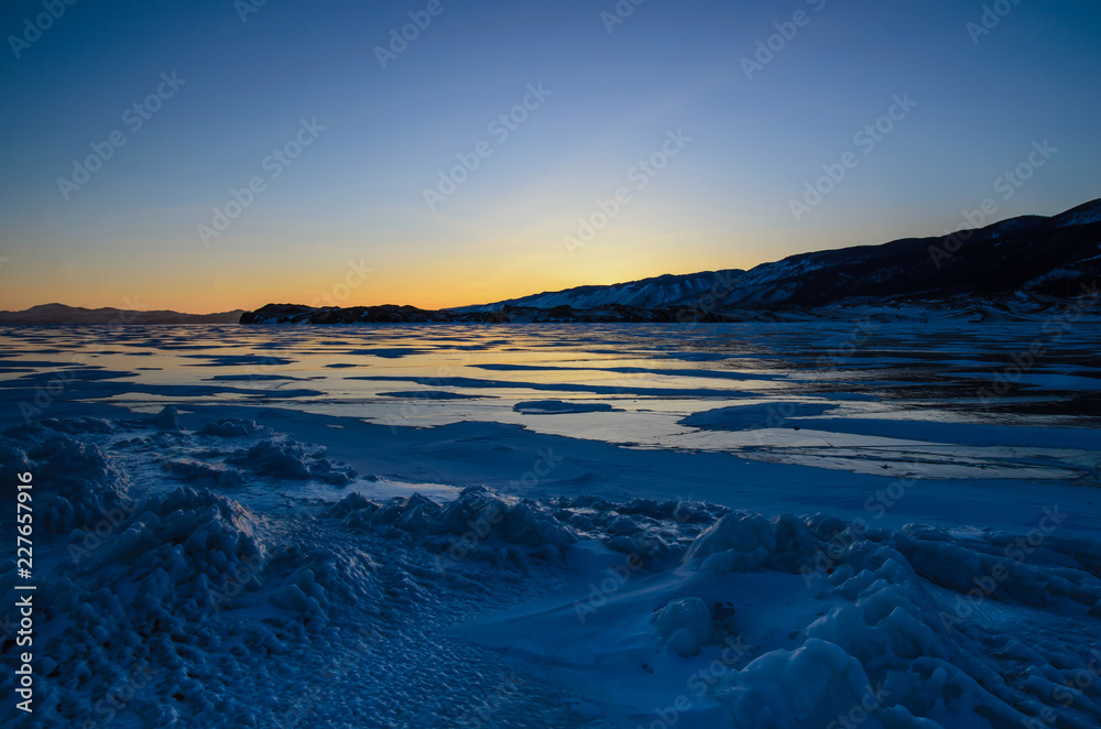 View of the ice and the rising sun over the mountains, lake Baikal