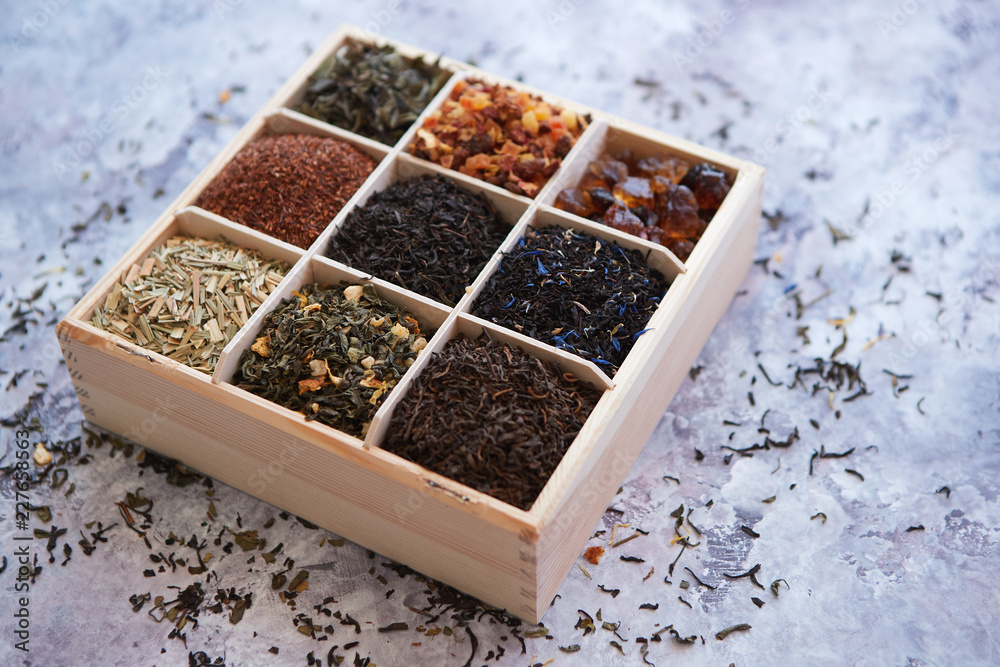 Various kind of dry tea - green, black, red, fruit and blue in wooden box on the table. Top view. Tea time concept. Various kind of dry tea - green, black, red, fruit and blue in wooden box on the table. Top view. Tea time concept.