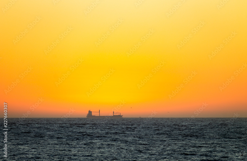 Distant Cargo Ship at Sunset