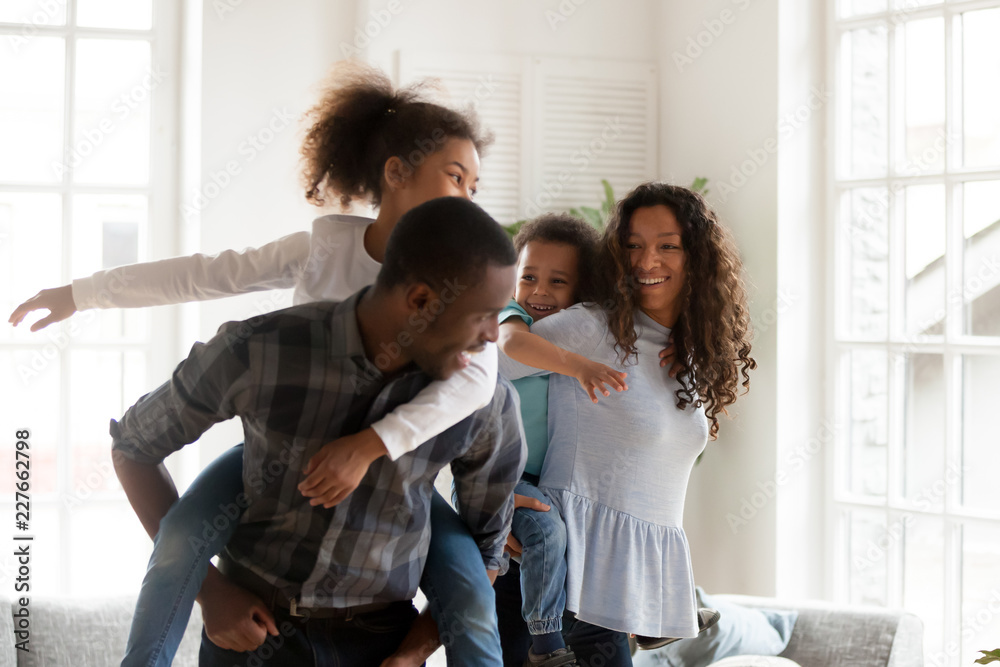 Φωτογραφία Playful laughing black family hugs with adorable little children have a fun standing in sitting room together at home