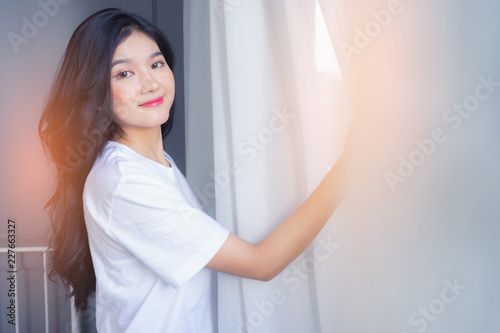 Woman stretching in bed after waking up, back view. Woman sitting near the big white window while stretching .she happy and smile.
