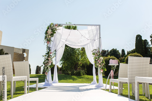 Outdoor wedding ceremony. Wedding chuppa decorated with fresh flowers photo