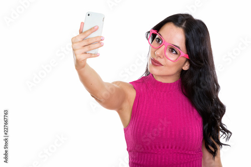 Studio shot of young beautiful Spanish woman taking selfie pictu
