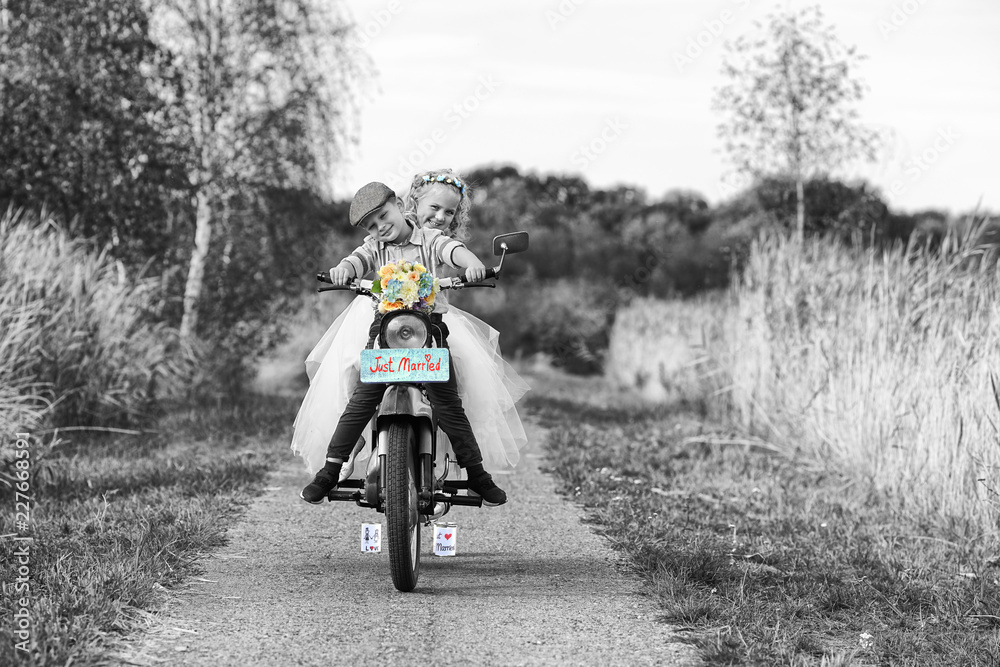 Naklejka premium 2 kleine Kinder fahren Moped bei der Hochzeit