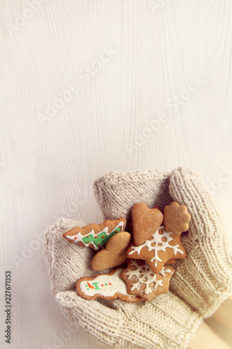  sweet winter holidays/ festive cookies decorated with icing in the hands dressed in mittens top view