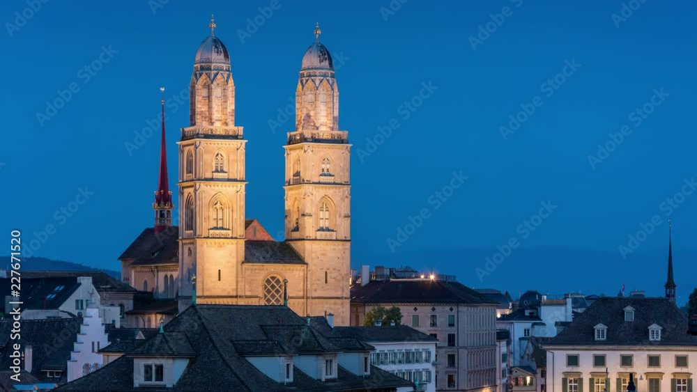  The Grossmunster church towers, one of the Zurich city symbols. Day to night time lapse video. Illumination and city lights switch on.