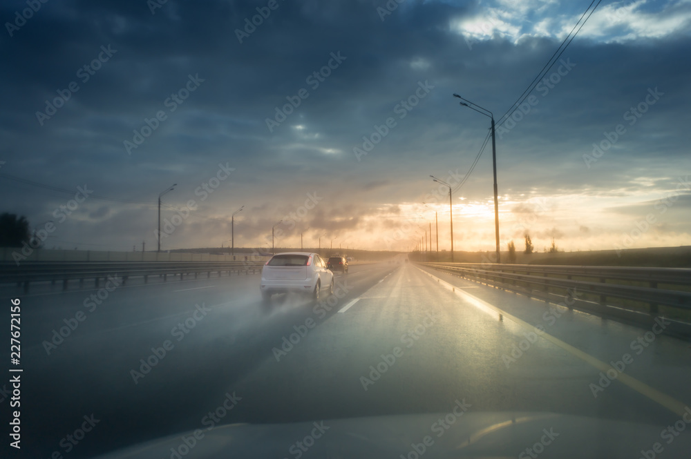 Drive car in rain on asphalt wet road. Clouds and sun.