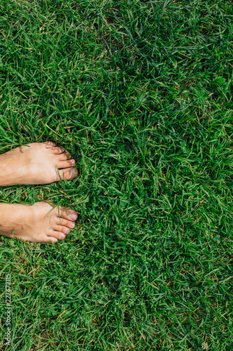 Bare woman's feet on the fresh green grass © Smile