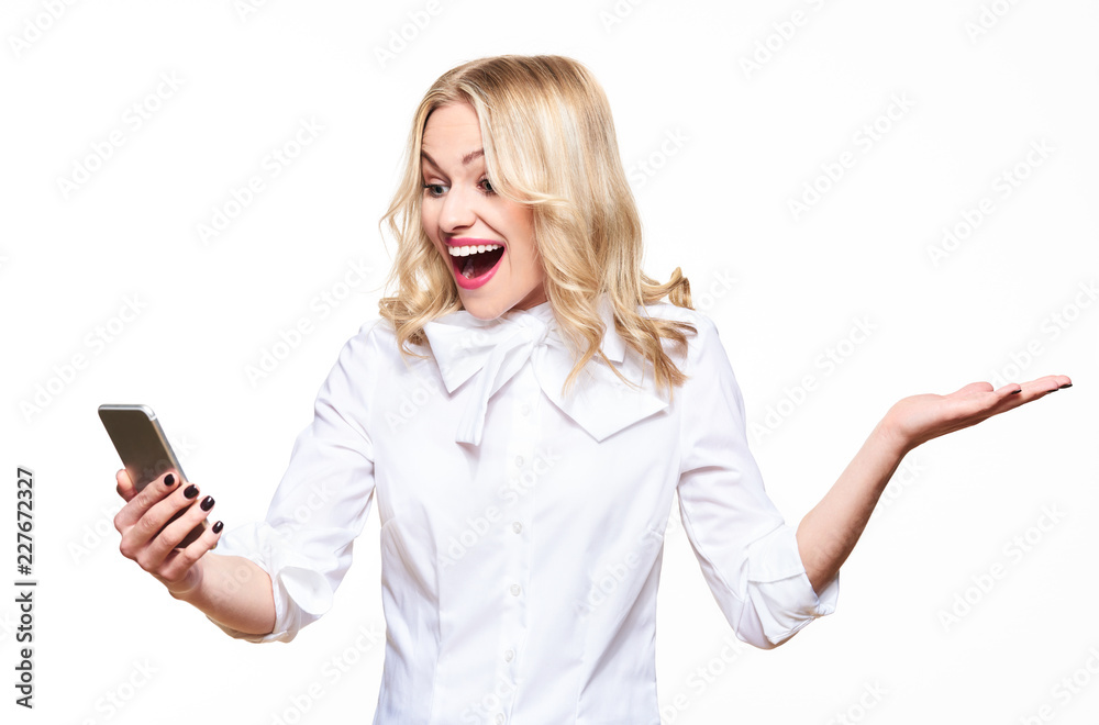 Young gorgeous woman looking at her smartphone over white background, screaming and celebrating victory and success. Very excited, cheering emotion. Young gorgeous woman looking at her smartphone over white background, screaming and celebrating victory and success. Very excited, cheering emotion.