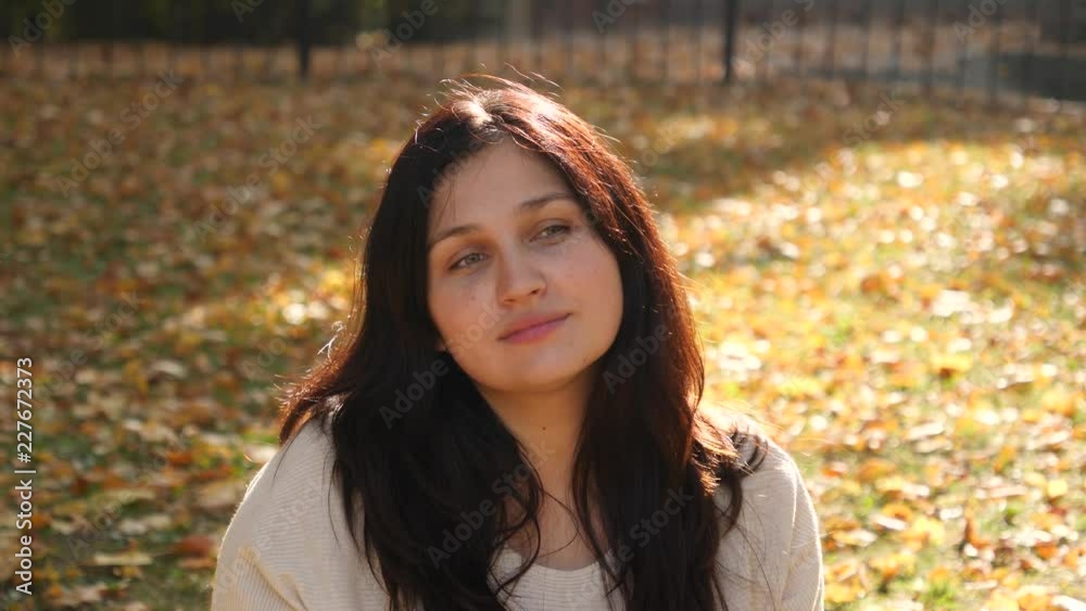 Brunette woman portrait sit on grass with fallen leaves admiring autumn yellow park bright sun light Brunette woman portrait sit on grass with fallen leaves admiring autumn yellow park bright sun light