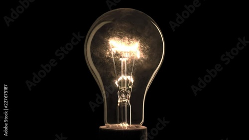Realistic light bulb blinking on black background. photo