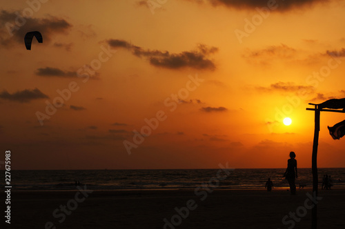 Kitesurfer and girl silhouette on sunset background, India, Goa