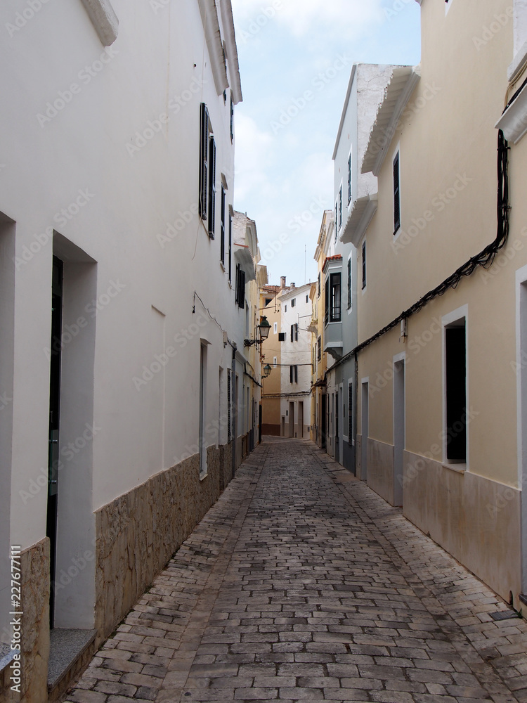 a typical narrow cobbled street of traditional painted houses in ciutadella menorca