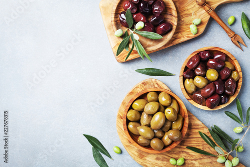 Marinated olives in bowls on kitchen board from olive wood top view.